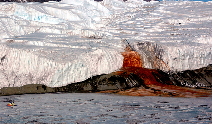 The Blood Falls seeps from the end of the Taylor Glacier into Lake Bonney. The tent at left provides a sense of scale for just how big the phenomenon is. Scientists believe a buried saltwater reservoir is partly responsible for the discoloration, which is a form of reduced iron.